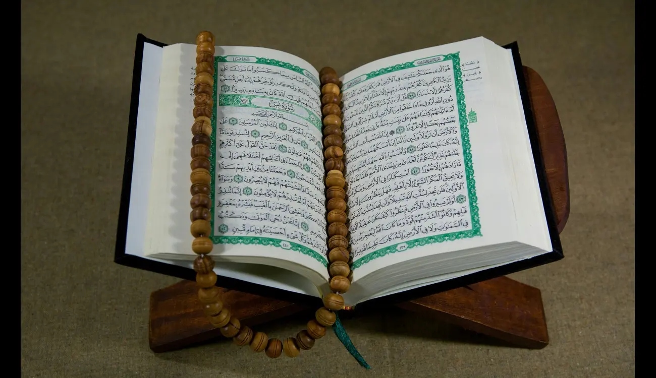 The Holy Quran on a stand using prayer beads as a book mark